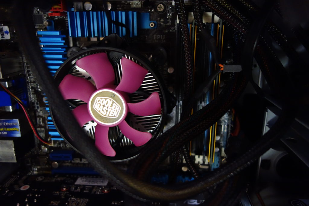 自作PCの内部の写真。 中央に紫色のファンのCPUクーラーがある。 クーラーの右横に黄金色のヒート シンクが付いたメイン メモリーが2枚挿入されている。 奥にマザーボードがある。