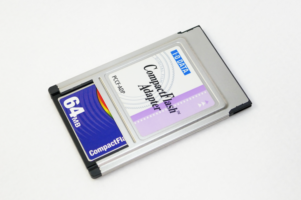 CompactFlashアダプターを撮影した写真。 PC Cardスロット差し込み用端子の側を右上向きにして置かれている。 向かって左下側にCompactFlashメモリー カードが装着されている。