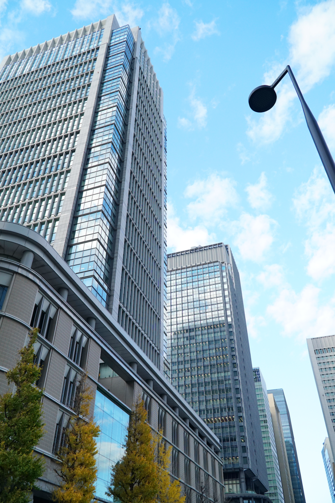 東京、 丸の内のビルディングを撮影した写真。 幾棟かの天空を突くような高層ビルディングが並んでいる。