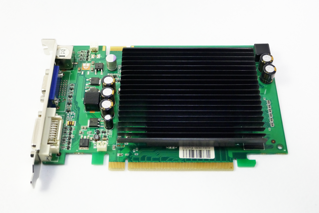 Palitのファンレス ヴィデオ カードであるGeForce 9400GT Superを撮影した写真。 黒色の多数の板が連なった形状のヒート シンクが搭載されている。 ブラケットを左側にして置かれている。