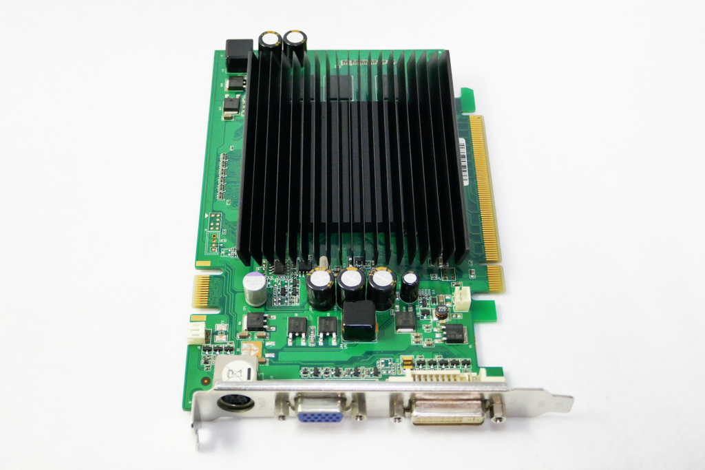 Palitのファンレス ヴィデオ カードであるGeForce 9400GT Superを撮影した写真。 黒色の多数の板が連なった形状のヒート シンクが搭載されている。 ブラケットを手前側にして置かれている。