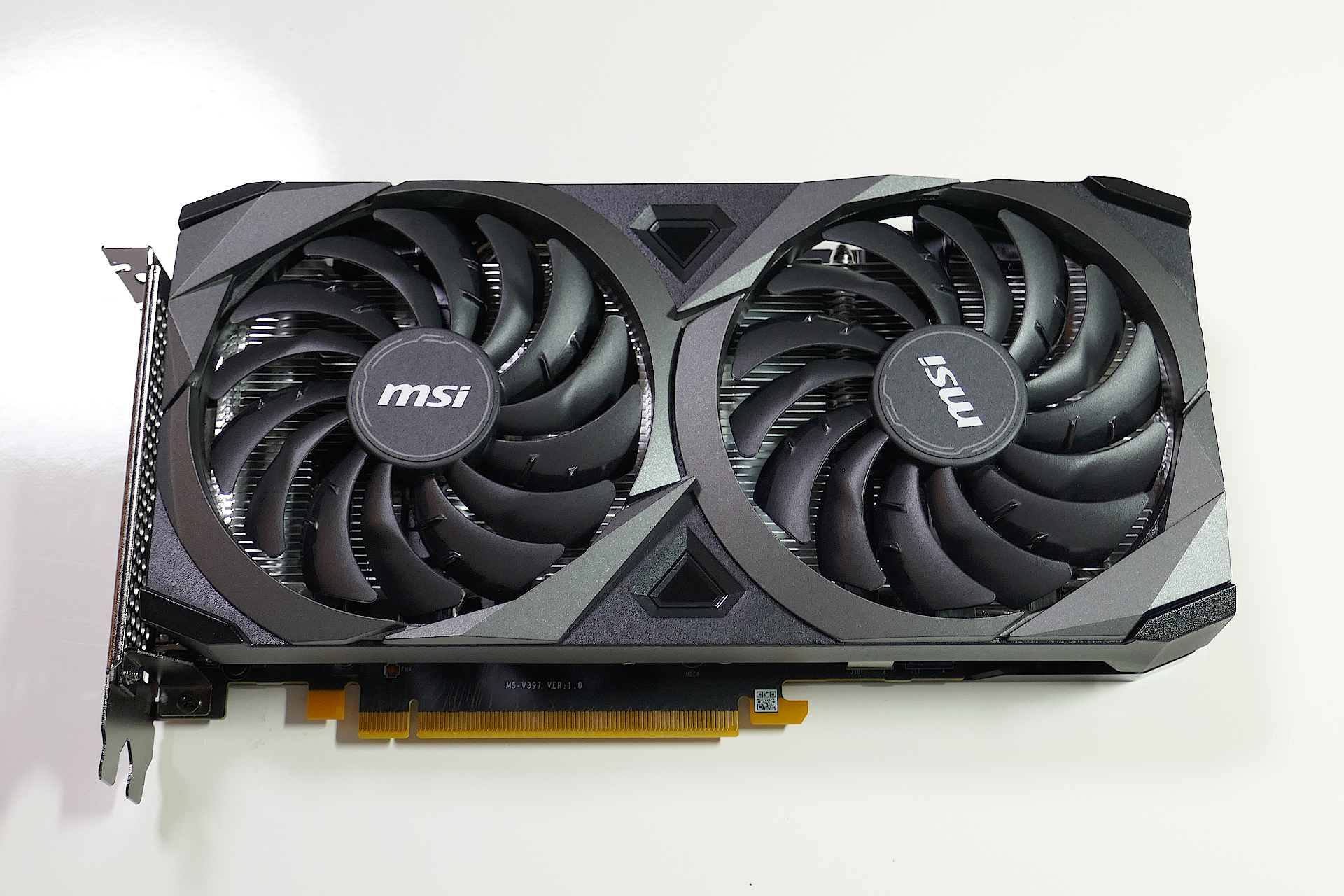 グラフィクス カードのMSI GeForce RTX 3060 VENTUS 2X 12G OCを正面上方から撮影した写真。 黒色のシェルに多数のブレードが有る2基のファンが搭載されている。