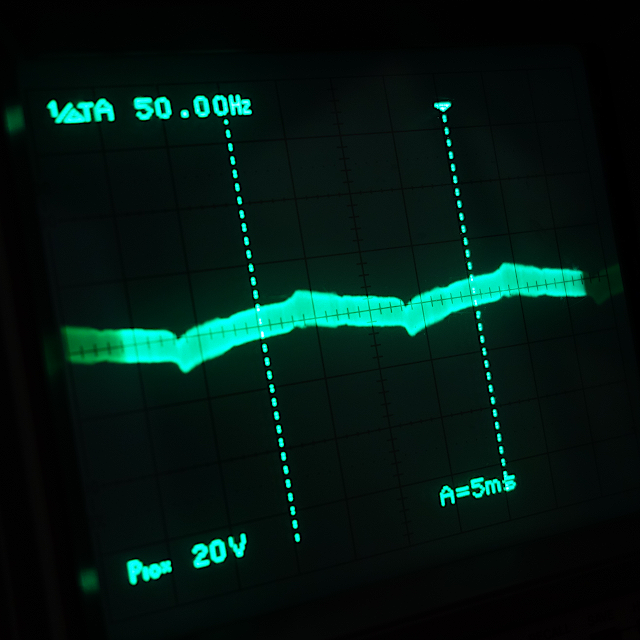 オシロスコープの画面の写真。 歪なノイズ波形が映し出されている。 周波数は50Hzと表示されている。