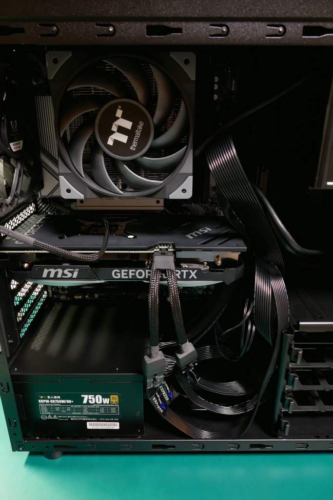 自作PC内部を撮影した写真。全体的に黒色で纏まっている。上方にCPUファンとケース ファン、中央にグラフィクス カード、底部に750W電源が搭載されている。